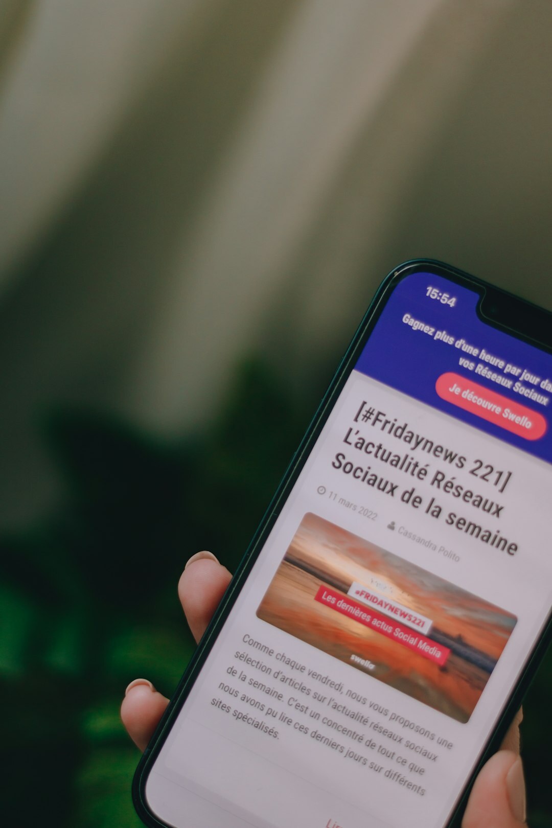 Hand holding a smartphone reading news articles